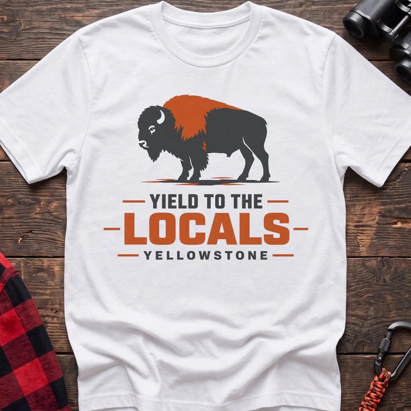 White cotton t-shirt with a bison graphic and Yield to the Locals Yellowstone text on rustic wood