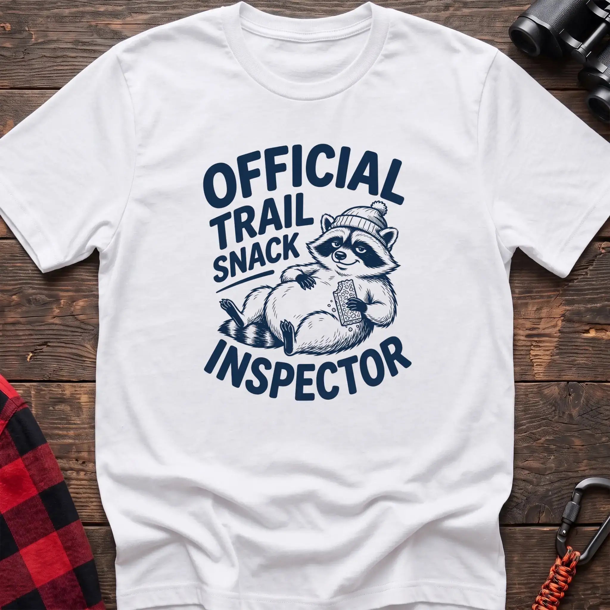 White t-shirt with cartoon raccoon holding a snack and the text Official Trail Snack Inspector